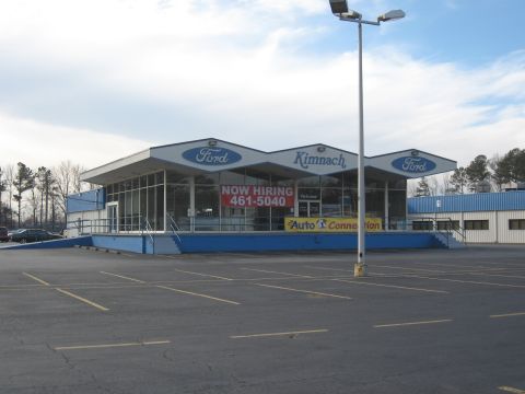 1968 Shelby GT500 - A Kimnach Ford dealership is shown with a parking lot and a dark sedan in the distance.