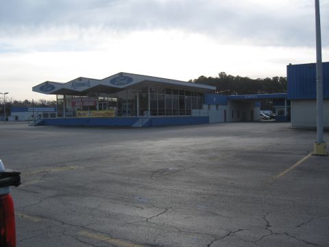 1968 Shelby GT500 - The exterior of a Ford dealership with a large lot and a sign advertising job openings.