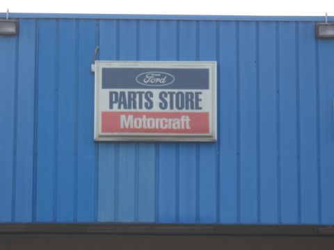 1968 Shelby GT500 - A sign for a Ford Parts Store with Motorcraft branding is mounted on a blue corrugated metal building.