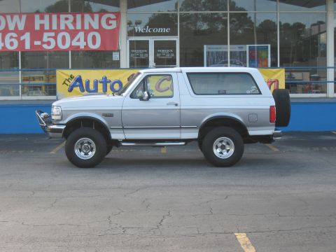 1968 Shelby GT500 - This Ford Bronco is parked in front of a business with a large banner and a spare tire mounted on the back.
