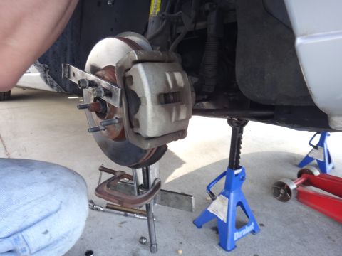 2000 Lincoln Continental - Car brake caliper and rotor assembly being worked on with tools and jack stands.