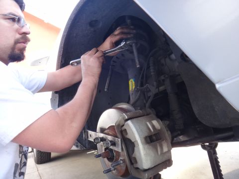 2000 Lincoln Continental - A person is shown performing maintenance on the suspension system of a vehicle, focusing on the strut assembly.