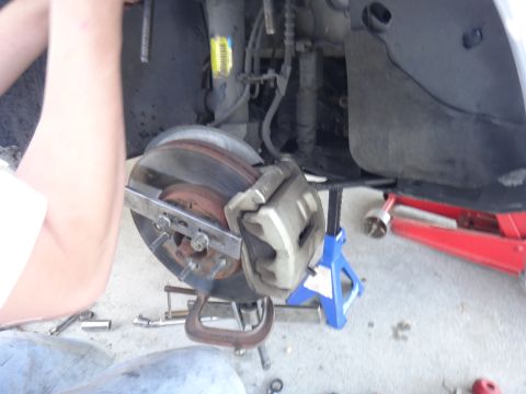 2000 Lincoln Continental - Close-up of a car's brake system being serviced, with tools and equipment visible.