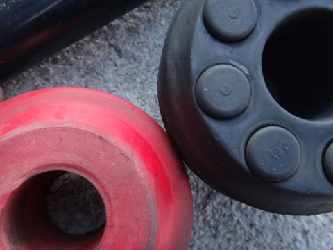 2000 Lincoln Continental - Close-up of two rubber suspension bushings, one red and one black, resting on concrete.