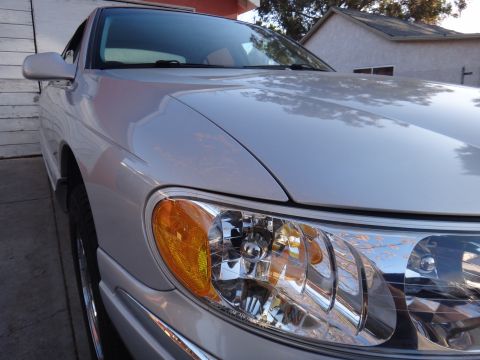 2000 Lincoln Continental - The front passenger side of a silver 2000 Lincoln Continental sedan is visible, with a focus on the headlight assembly.