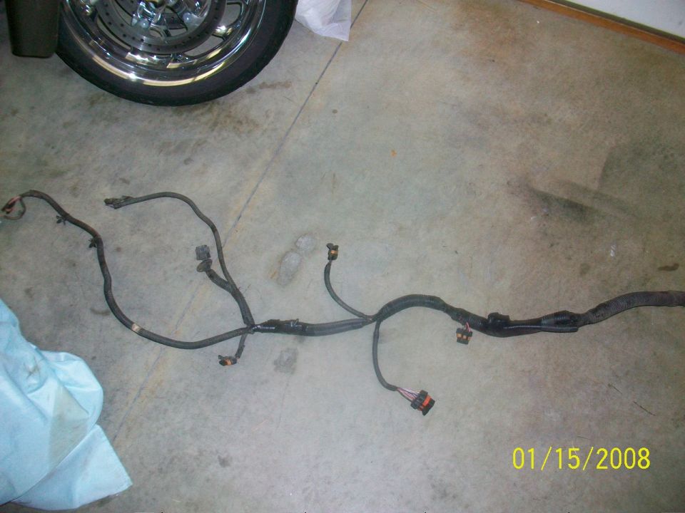Wiring harness laid out on a concrete floor next to a motorcycle wheel