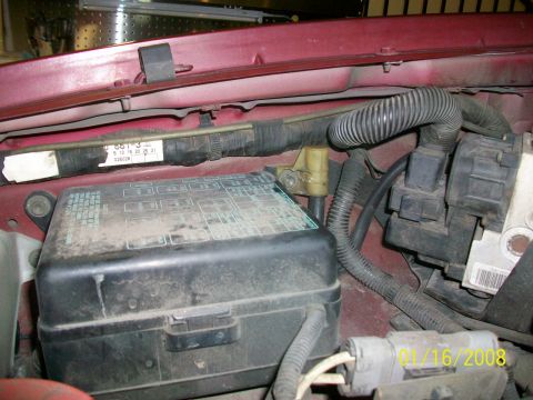 2000 Isuzu Vehicross - Close-up view of the engine bay, showing a fuse box, wiring harness, and a label with text.