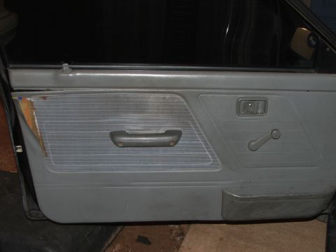 1991 Ford Festiva - The interior door panel shows wear and tear, with a torn section on the left side.
