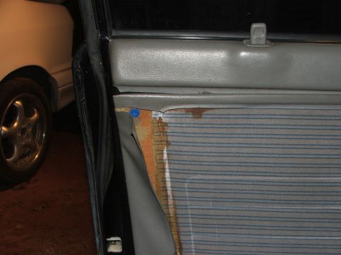 1991 Ford Festiva - Interior view of a car door panel showing damage and a partial view of another vehicle.