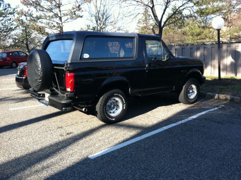 1996 Ford Bronco - A black 1996 Ford Bronco is parked in a lot with a spare tire mounted on the rear.