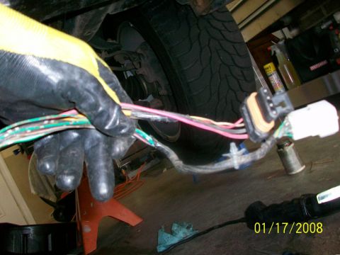 2000 Isuzu Vehicross - A close-up view of a vehicle's wiring harness being worked on, with a tire and suspension components in the background.