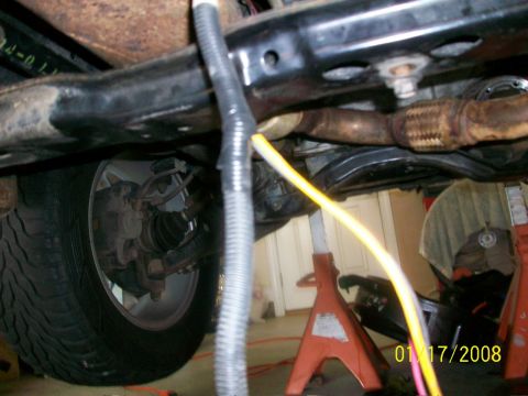 2000 Isuzu Vehicross - A close-up view of a vehicle's undercarriage, revealing suspension components, exhaust system, and a tire.