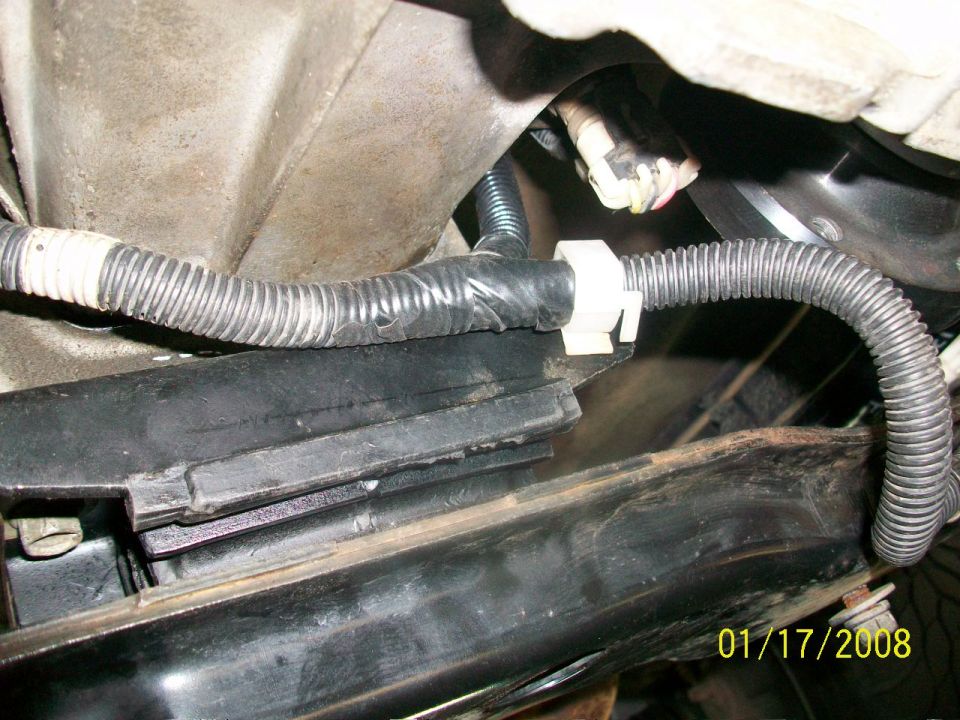 Close-up of a vehicle's wiring harness secured by a white clip to a black frame component. Date stamp reads 01/17/2008
