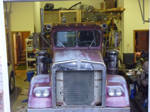1959 Kenworth W900A - This truck is in a garage, undergoing some work. The grille is missing, and the paint is worn.