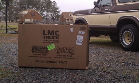 1979 Ford Bronco - A large box of LMC Truck parts sits on the ground next to a classic Ford Bronco.