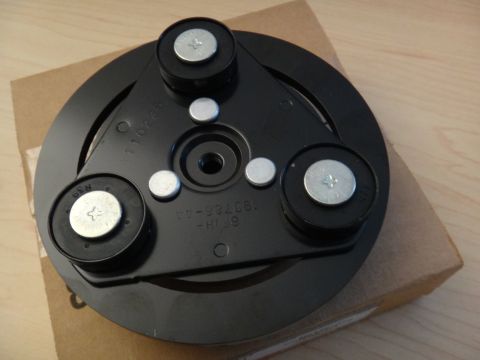 2003 Ford Taurus - A black AC clutch hub with visible part numbers and bolt heads is shown against a plain background.