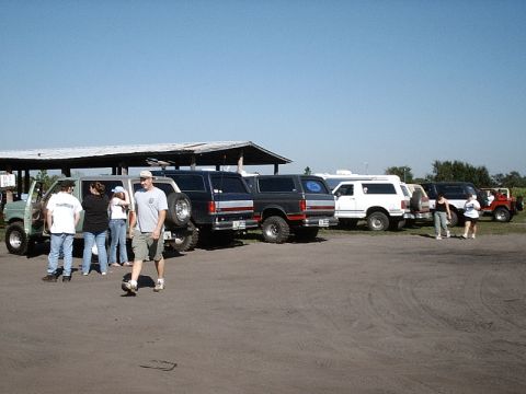 1996 Ford Bronco - A group of SUVs and trucks are parked outdoors under a clear blue sky.