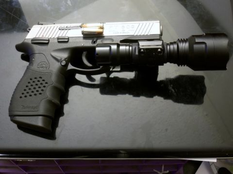 2000 Mercury Grand Marquis - A pistol with a mounted flashlight is shown against a dark background.