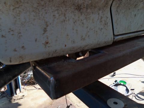 1989 Ford Bronco - Close-up of a vehicle's side, showing a dirty body panel and custom metal undercarriage modifications.