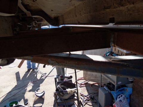1989 Ford Bronco - A view of the underbody frame and suspension components, with various tools and equipment visible on the ground below.