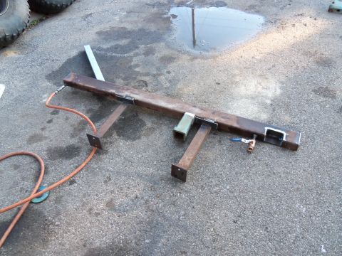 1989 Ford Bronco - A metal frame with an attached air hose and valve sits on a wet asphalt surface.