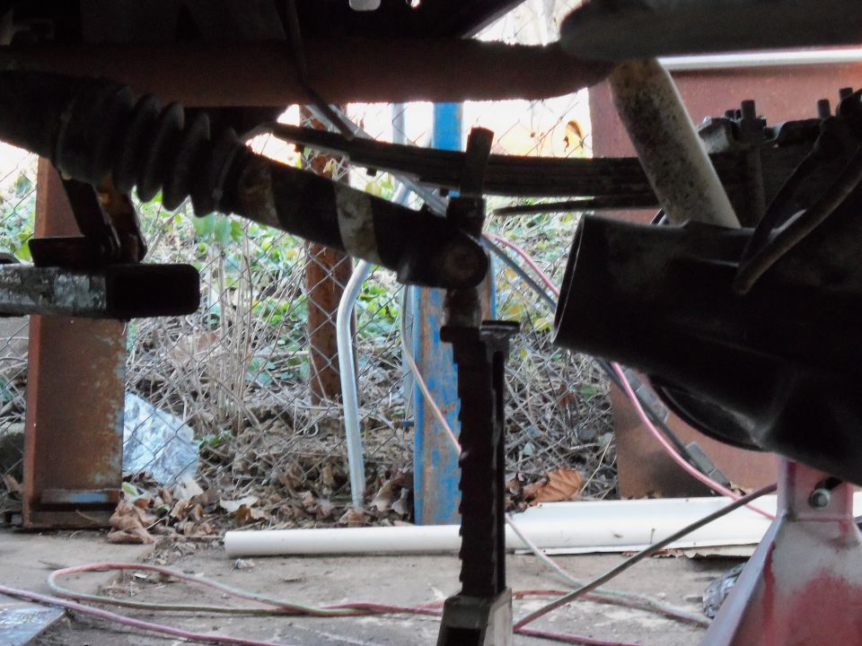 Close-up of a vehicle's rear axle assembly, showing suspension parts and a driveshaft