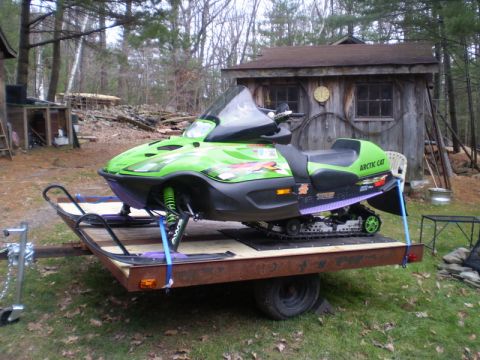 1979 Ford Bronco - Arctic Cat snowmobile loaded onto a trailer, ready for transport. The scene is set in a rural outdoor location.