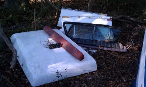 1979 Ford Bronco - Vehicle parts including a camper shell and tailgate are piled up outdoors.