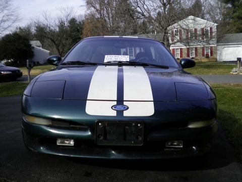 1997 Ford Probe - A dark green Ford Probe with white racing stripes is parked in a driveway.