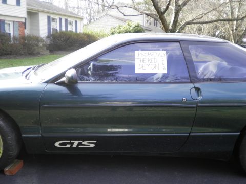 1997 Ford Probe - Side view of a green coupe with a handwritten sign in the window that reads "PROBE TALK THE RED DEMON".