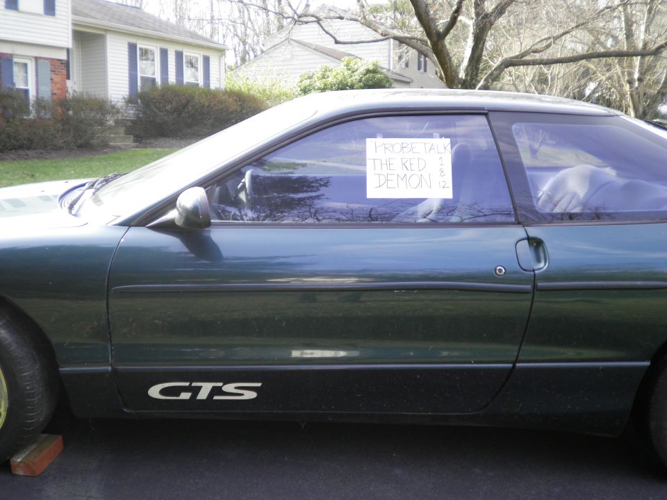 Green coupe side view with "PROBE TALK THE RED DEMON" sign in window