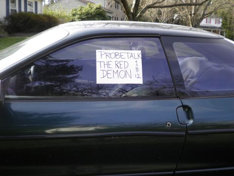 1997 Ford Probe - Side view of a dark green coupe with a handwritten sign on the driver's side window.