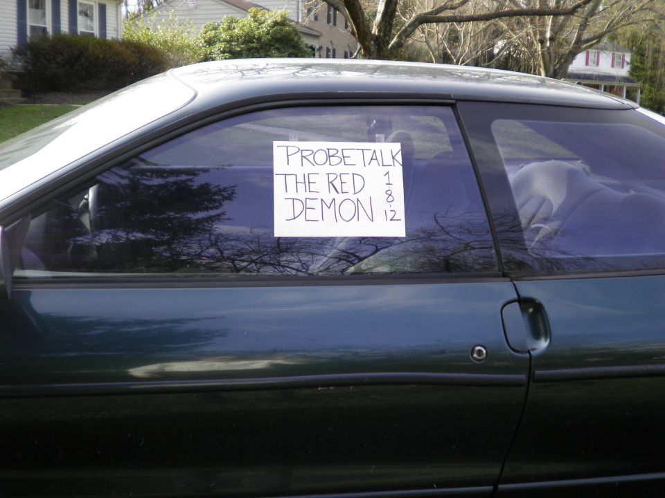 Dark green coupe side view, sign on window reads 'PROBETALK THE RED DEMON 1 8 12'