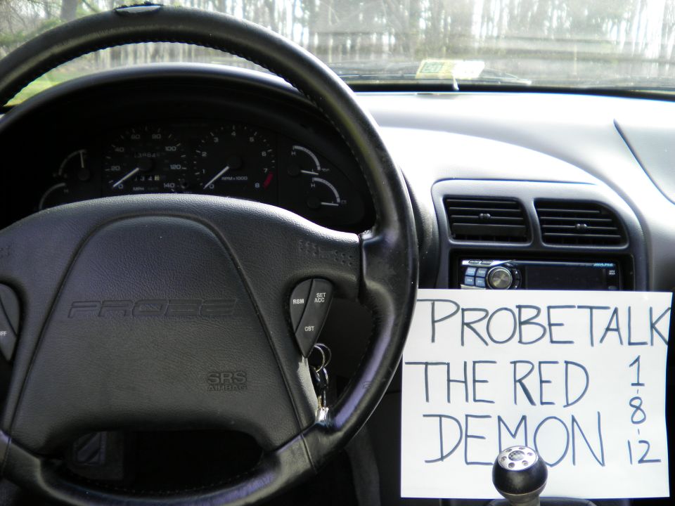 Interior of a 1997 Ford Probe showing the steering wheel, dashboard, and a handwritten sign