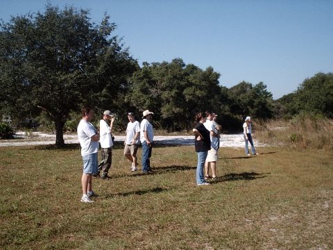 1996 Ford Bronco - A group of people stand in a grassy outdoor area under a clear blue sky, with trees in the background.