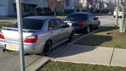 1999 Mercury Grand Marquis - A silver Subaru Impreza WRX is parked on the street, with a dark sedan behind it.