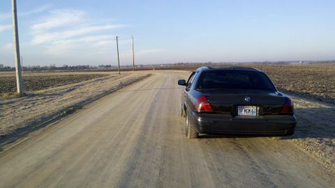 1999 Mercury Grand Marquis - Rear view of a 1999 Mercury Grand Marquis on a dirt road with fields in the background.