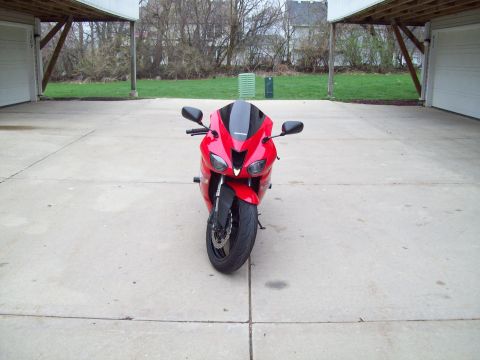1999 Mercury Grand Marquis - A red sport motorcycle is parked on a concrete driveway in front of a grassy area and houses.