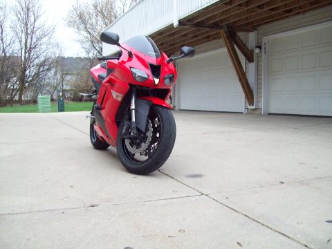 1999 Mercury Grand Marquis - A red sport motorcycle is parked on a concrete driveway in front of a two-car garage.