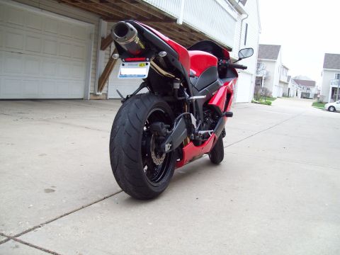 1999 Mercury Grand Marquis - Rear view of a red sport motorcycle with a custom exhaust parked in front of a garage.