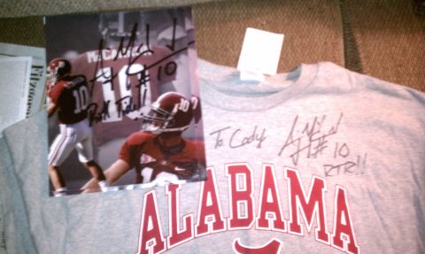 2004 Aston Martin Virage - A signed photograph of an Alabama football player is displayed on a gray t-shirt with the team name and additional signatures.