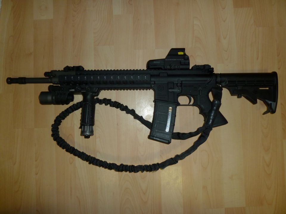 AR-15 style rifle with red dot sight, tactical grip, and sling