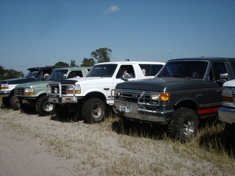 1996 Ford Bronco - Several Ford Broncos are parked in a line on a sunny day.
