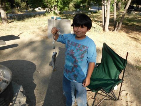 1988 Ford Bronco - A young boy proudly displays his catch of two fish while standing next to a camping chair.