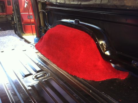 1991 Ford Bronco - The cargo area of a 1991 Ford Bronco features red carpet covering the wheel well.