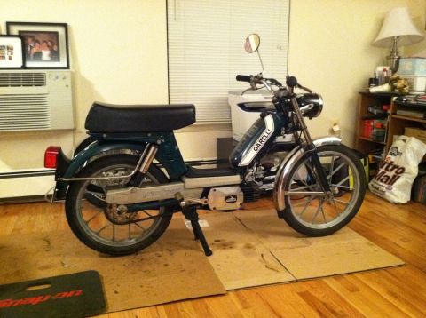 1981 Garelli Rally Sport - A dark green moped with chrome accents is parked on a wooden floor, resting on cardboard.