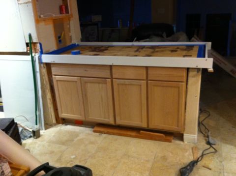 1989 Yugo Cabrio - Construction scene shows a partially built kitchen island with cabinets and a taped plywood countertop.