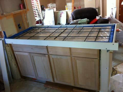 1989 Yugo Cabrio - A kitchen island is being constructed, with cabinets installed and a rebar grid laid out on top, ready for concrete.