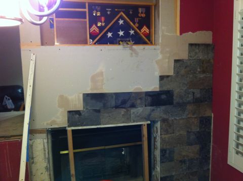 1989 Yugo Cabrio - A fireplace is being renovated with stone tiles, and a framed American flag with military medals is displayed above.