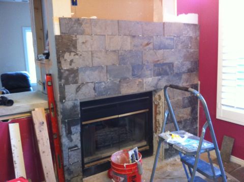 1989 Yugo Cabrio - Construction scene shows a fireplace being tiled with slate, a red bucket of supplies and a stepladder.